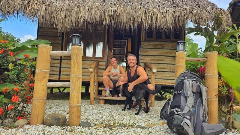 La pareja con sus morrales en la terraza de una cabaña